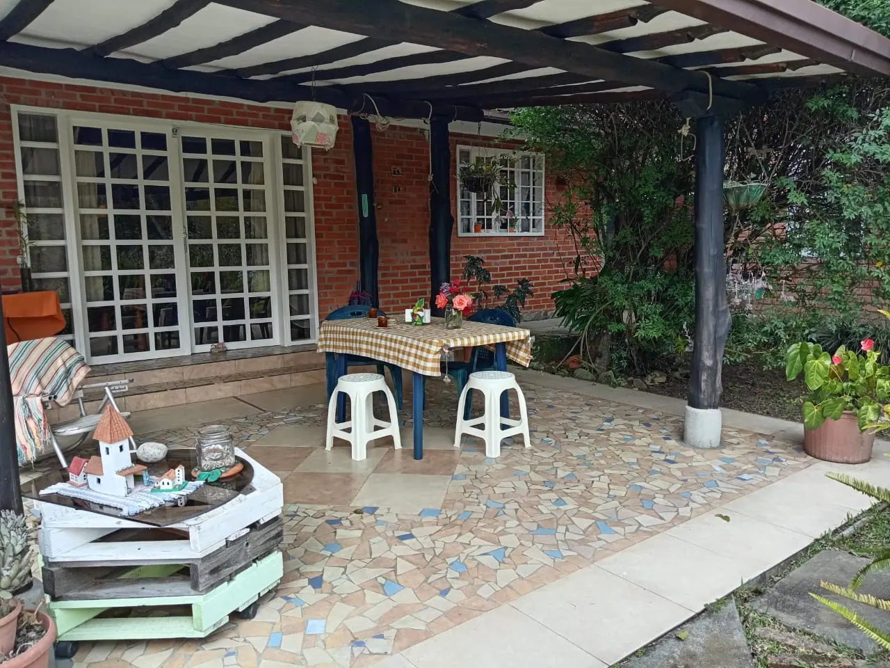 Desayuno con jugo sobre mesa exterior rodeada de árboles rojos y jardín verde