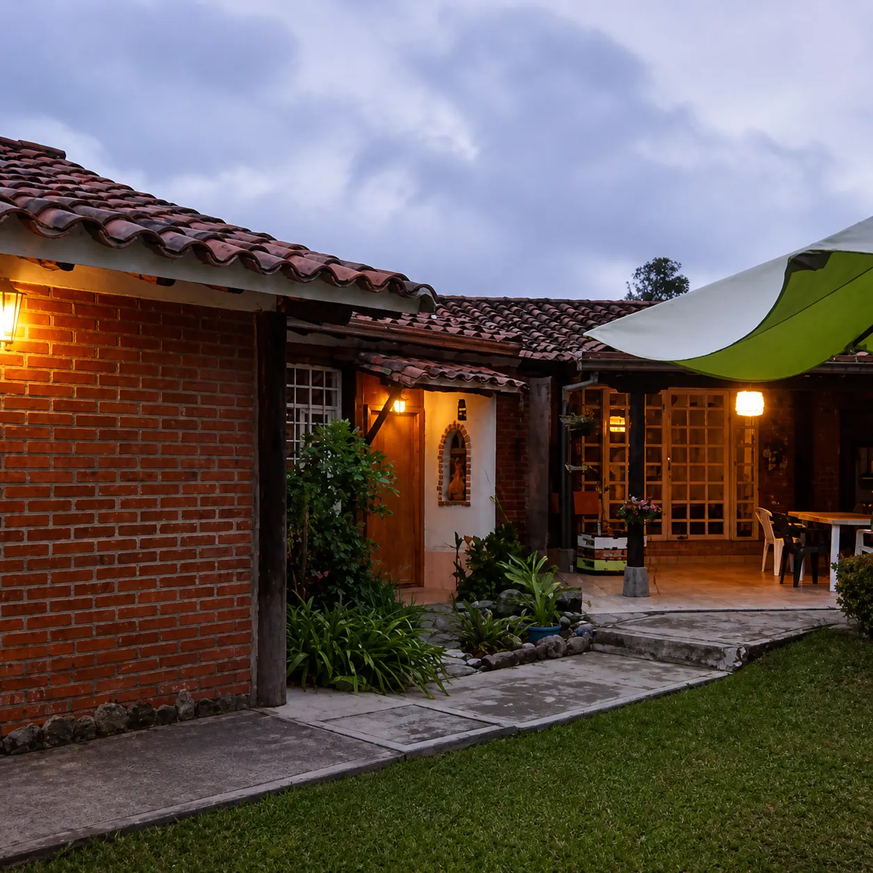 Jardín de La Tucanera con sillas, mesas, casa de ladrillo y cielo azul
