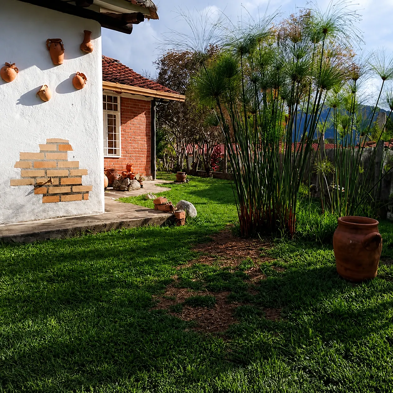 Mesa servida bajo sombrilla verde con jardín, flores y montañas al fondo
