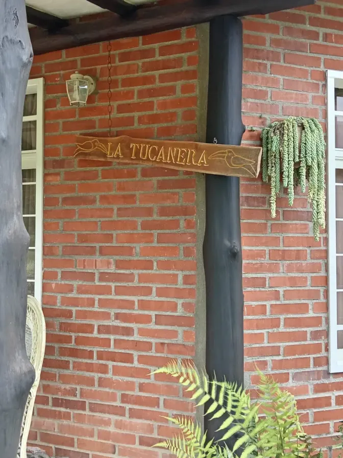 Entrada de ladrillo con el letrero de La Tucanera y plantas colgantes